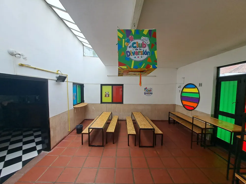 Comedor de los chicos con mesas largas, bancos de madera y piñata