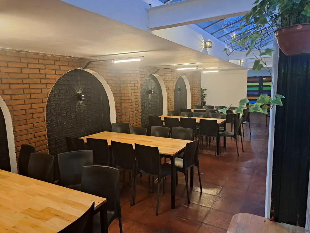 Comedor de los grandes con mesas de madera, sillas y techo con tragaluz