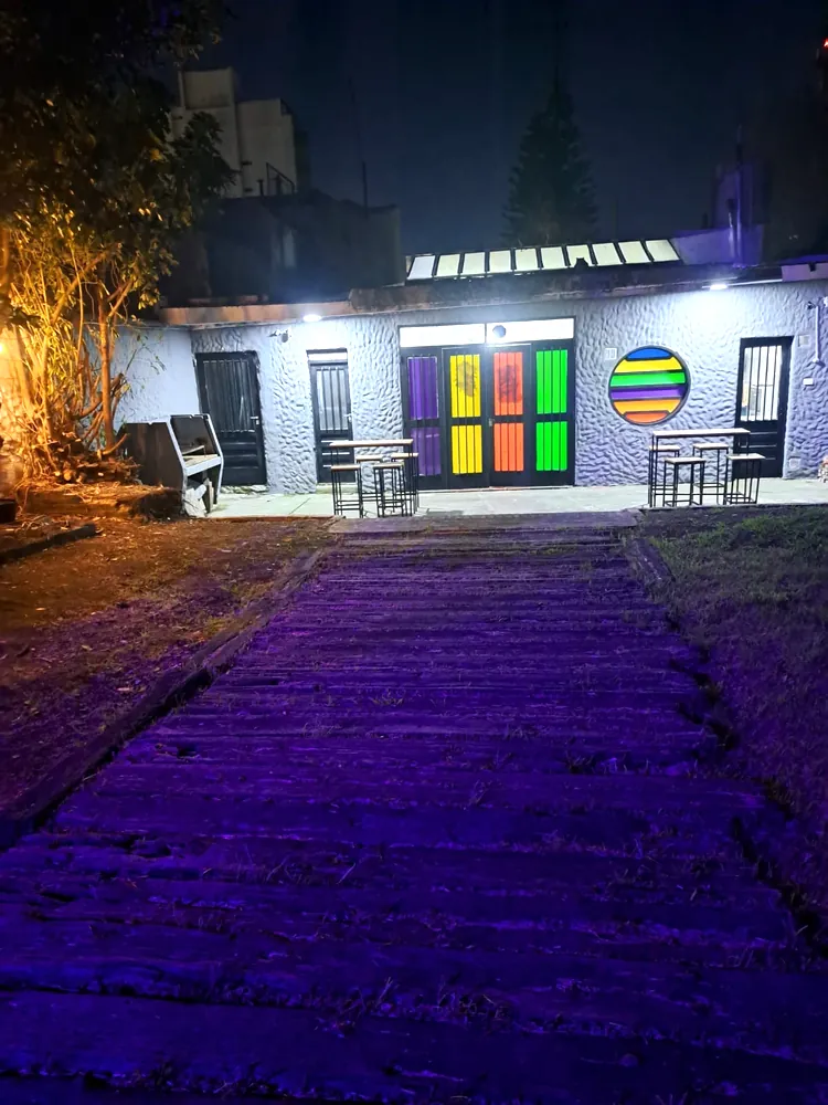 Patio de noche con luces cálidas y el frente de colores del club