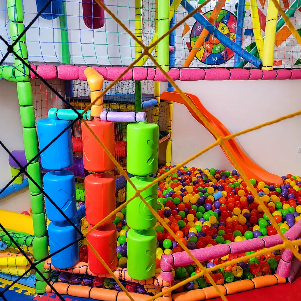 Laberinto de varios niveles con tubos de colores, red y tobogán sobre una piscina de pelotas